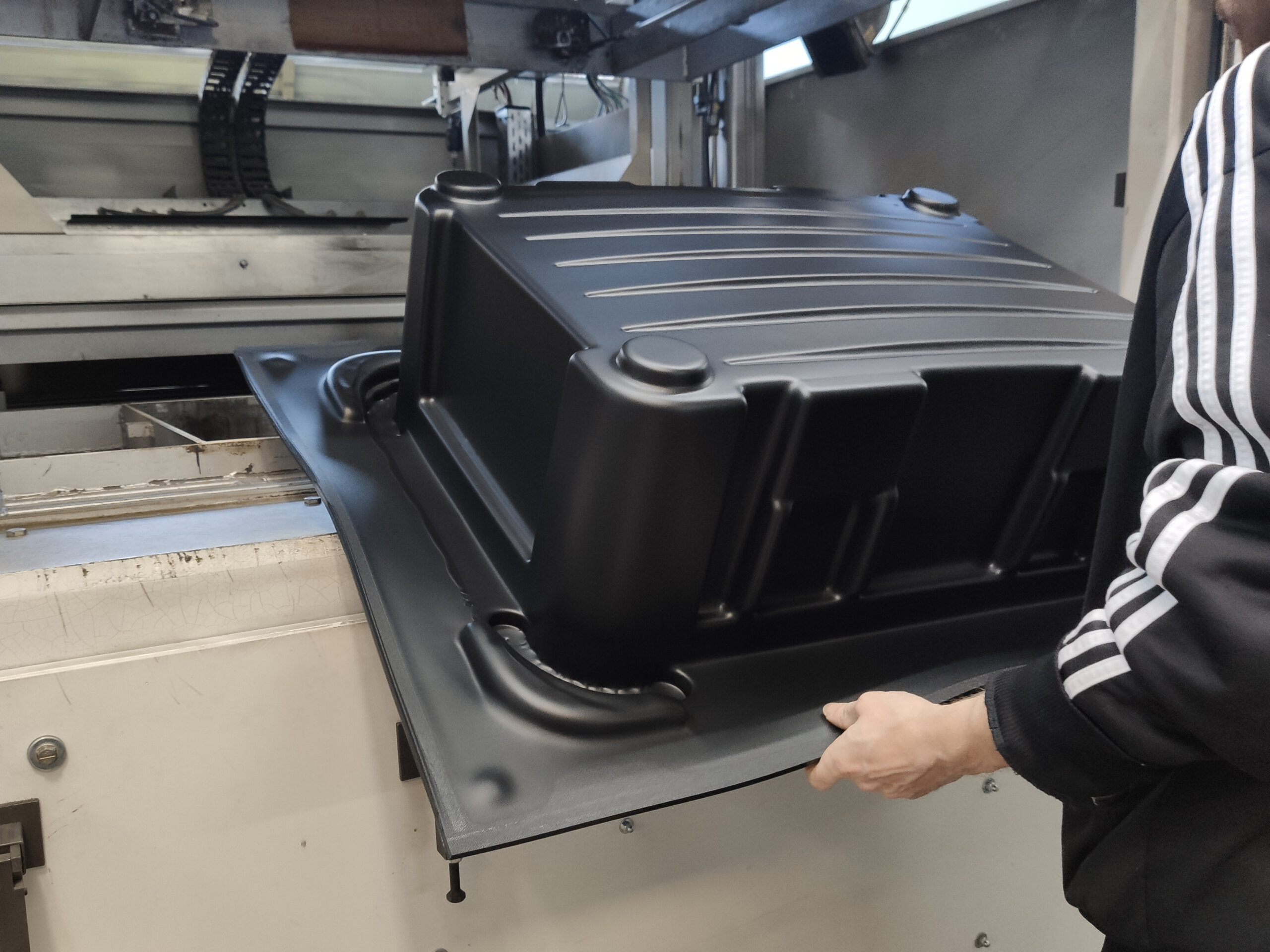 Ein Kofferschale aus Kunststoff wird aus der Tiefziehmaschine bei bwh Koffer herausgenommen